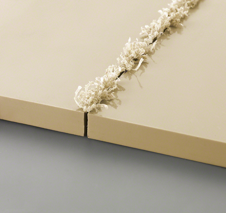 两块米色板材，边缘有新切出的凹槽和卷曲的木屑。