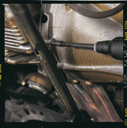 电钻正在拧紧金属发动机外壳上的螺丝。