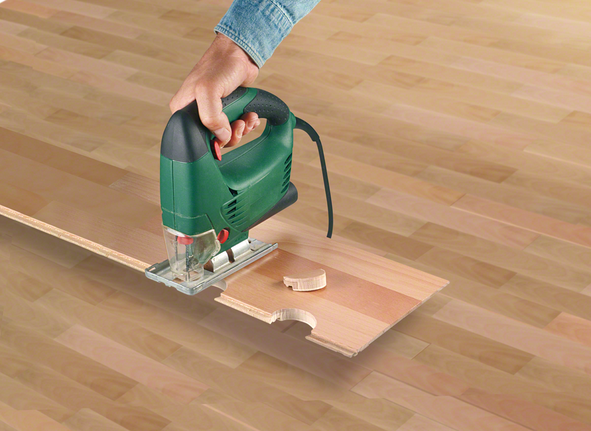 一个人用曲线锯在木板上切出一个圆形凹口。.