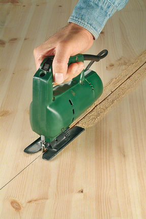 一个人引导拼图锯在木板上切出一条直线。.