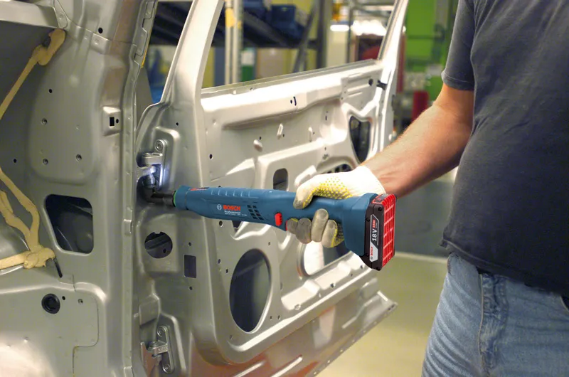 佩戴安全设备的人员使用无绳工具固定车门内的铰链。.