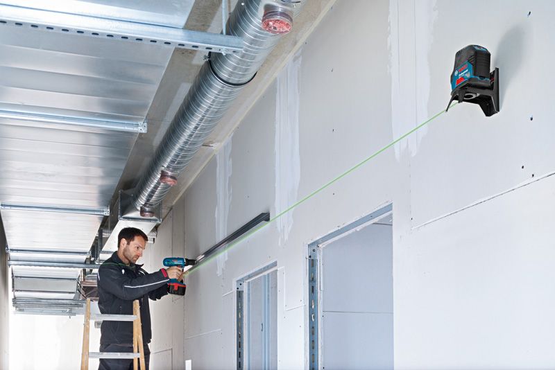 在绿色激光调平工具的引导下，工作人员使用钻头安装金属导轨。