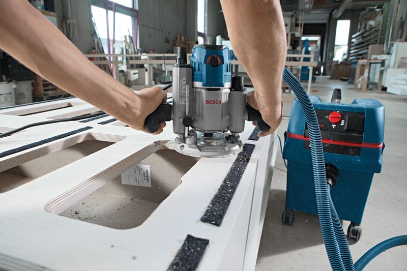 一名工人在车间使用电动铣刀雕刻木板。.