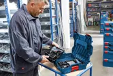 车间里的一名工人从硬塑料盒中取出一套无绳工具。.