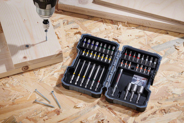 电钻/起子机放在胶合板表面上，旁边是螺丝和木板。