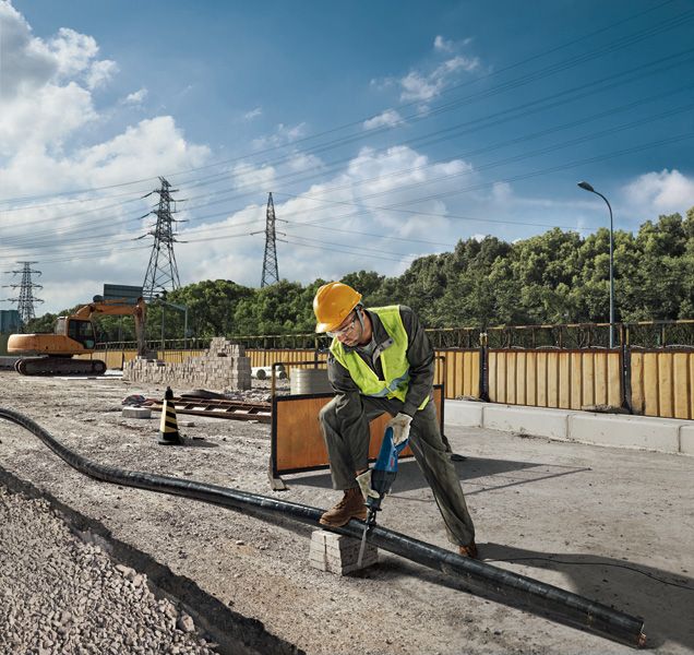 一名佩戴安全设备的人员在施工现场使用往复锯切割管道。.