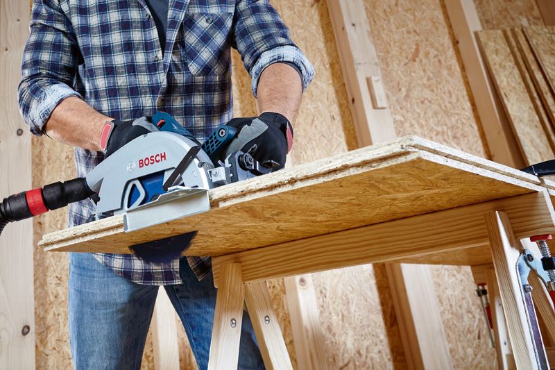 一名佩戴安全设备的人员使用圆锯切割木板。.