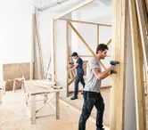 两名男子正在建造木墙。.