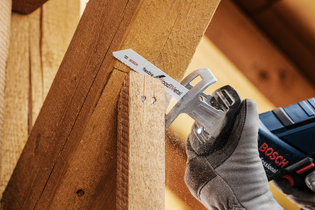 一名佩戴安全装备的人员用往复锯切割木梁。