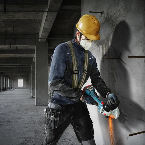 一名佩戴安全设备的人员正在使用角磨机切割混凝土。.