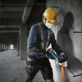 一名佩戴安全设备的人员正在使用角磨机切割混凝土。.