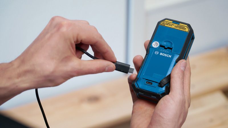 一个人将充电线连接到手持电动工具的背面。.