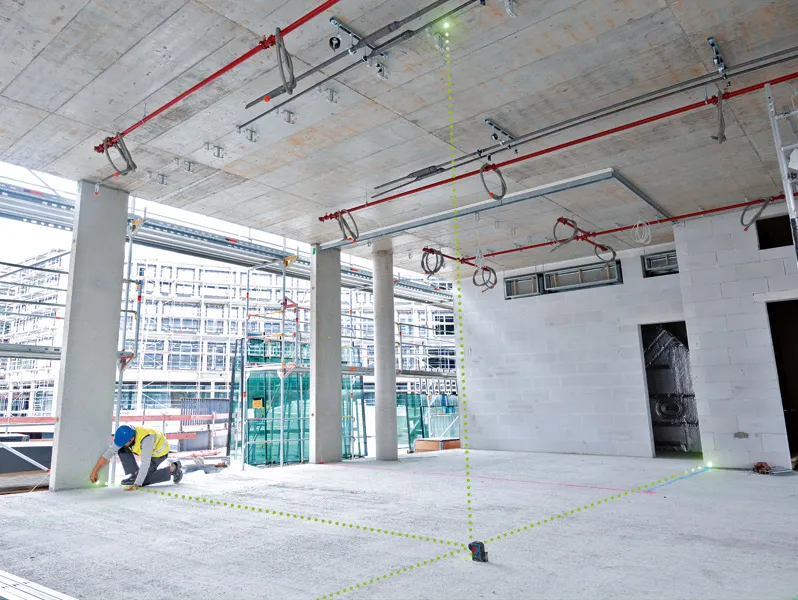 佩戴安全设备的人员使用激光调平工具来对准施工区域内的各点。