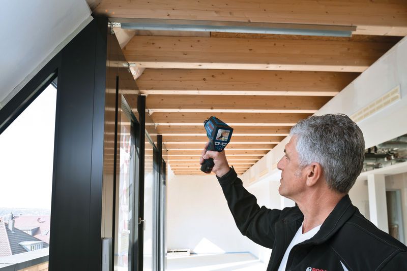 一个人用手持式检查设备扫描天花板横梁。