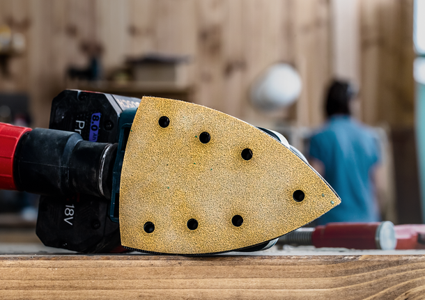 细节砂光机放置在车间的木质表面上，背景中有一个人物。