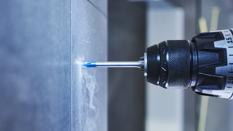 电钻在瓷砖墙上钻孔。