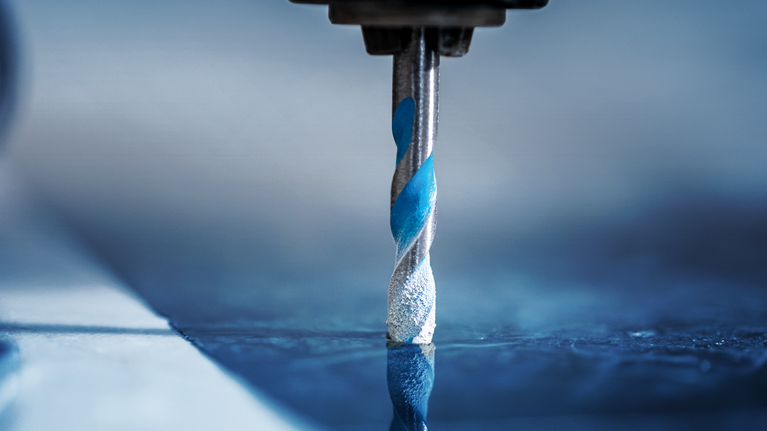 钻头在反光瓷砖表面上钻孔。