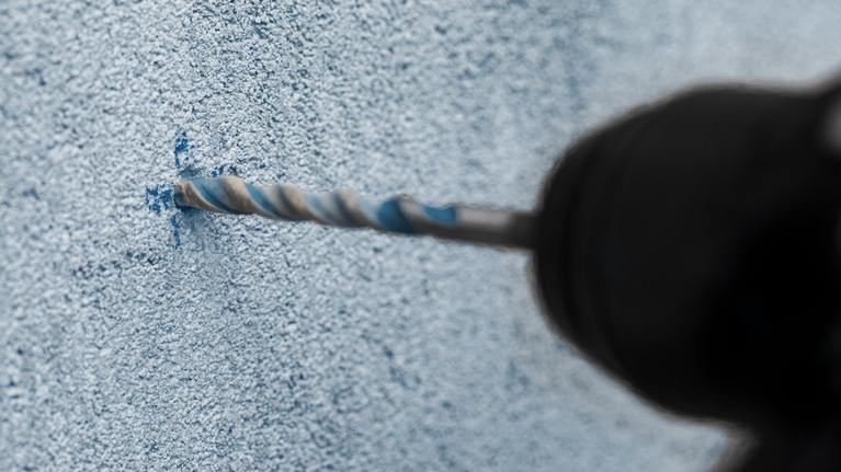 在有纹理的混凝土墙上钻孔。