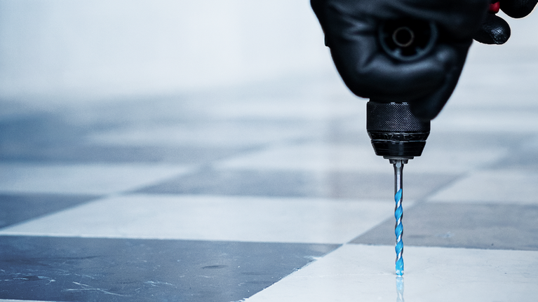 佩戴安全设备的人员正在钻瓷砖地板。