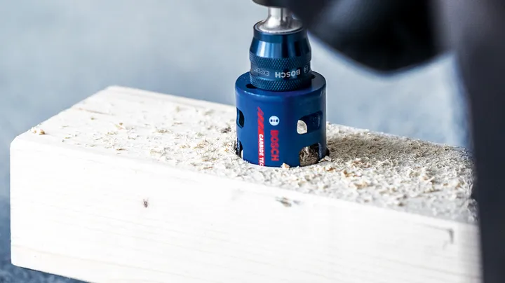 用孔锯在木板上钻一个圆形开口。