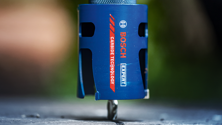 蓝色硬质合金孔锯钻入平面的特写。