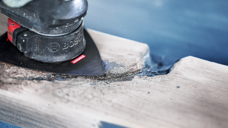 使用振荡多工具打磨和塑造一块木头。