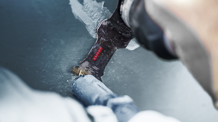 一个人用往复锯片切割涂漆的金属管。