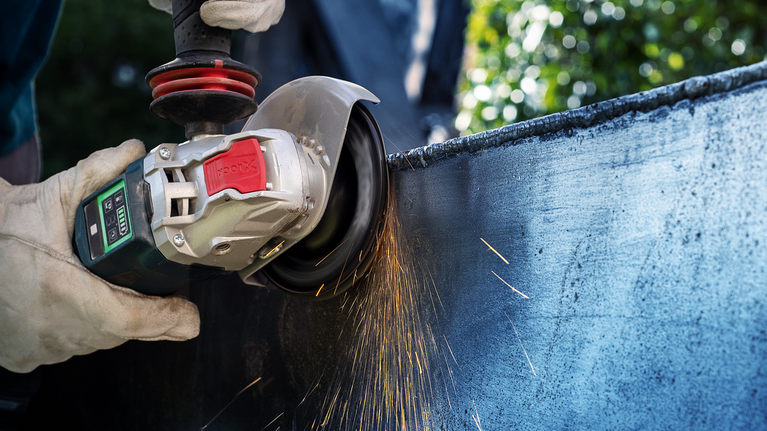 佩戴安全设备的人研磨金属，产生火花。