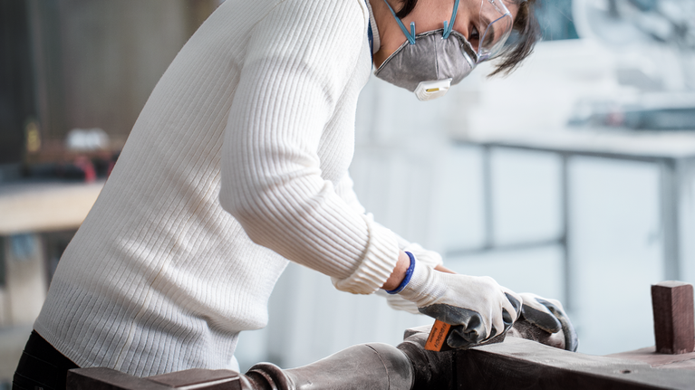 一名佩戴安全设备的人员在车间打磨金属表面。