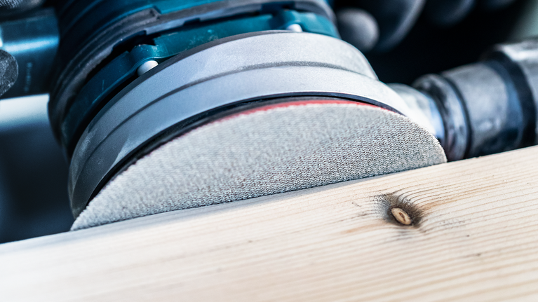 电动砂光机打磨木板表面。