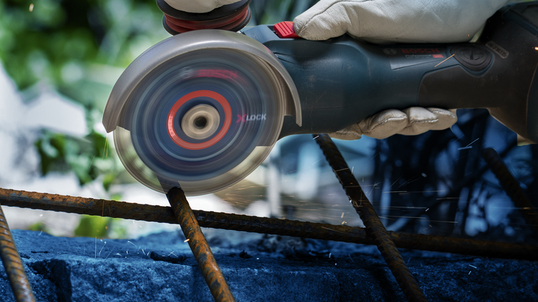 佩戴安全设备的人员使用角磨机切割生锈的钢筋。