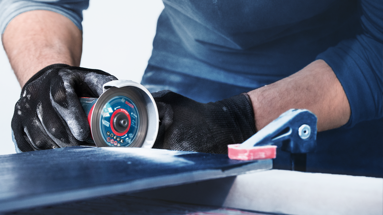 佩戴安全设备的人员使用电动工具切割瓷砖。