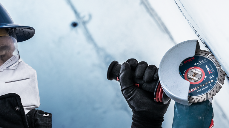 一名佩戴安全设备的人员使用角磨机切割金属表面。