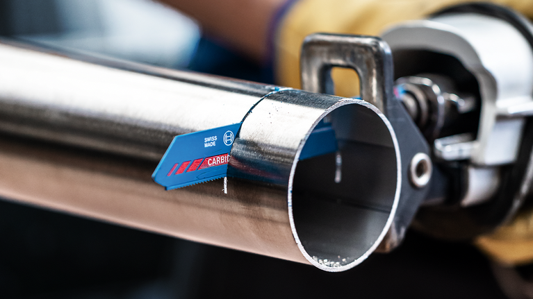 佩戴安全设备的人员使用往复锯切割金属管道。