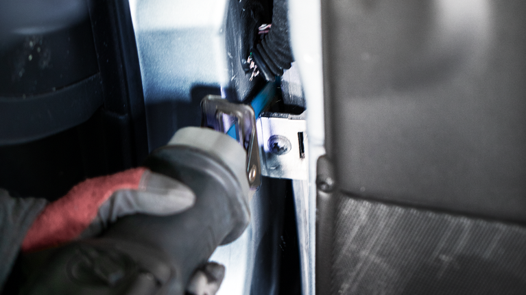 佩戴安全设备的人员使用往复锯切割车辆内部的金属。