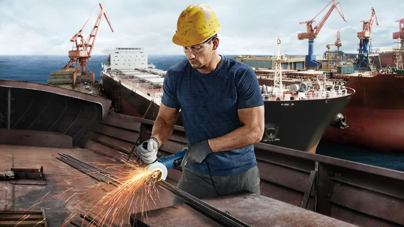 造船厂工人正在磨削金属。.