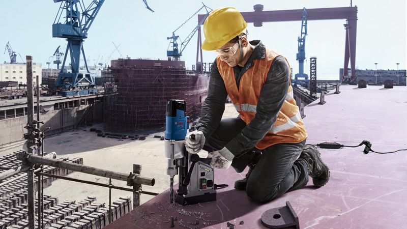 一名佩戴安全装备的人员正在建筑工地操作磁力取芯钻。