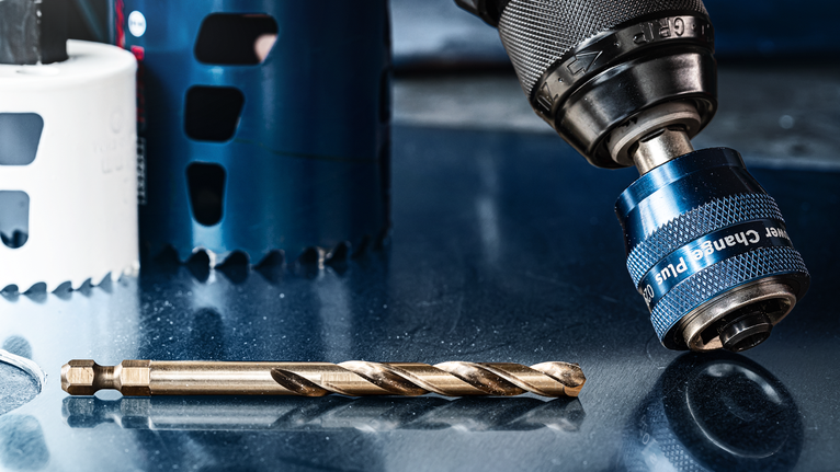 反光金属表面上的钻夹头和钻头的特写。