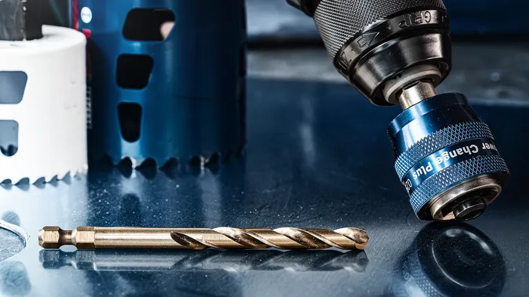 反光金属表面上的钻夹头和钻头的特写。