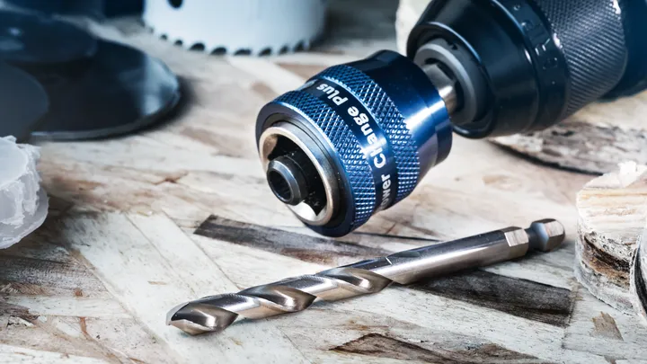 木质表面上带有金属钻头的钻夹头附件的特写。