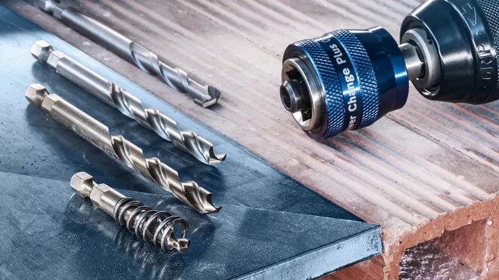 带有多个钻头的电钻驱动器放置在金属和砖块表面上。