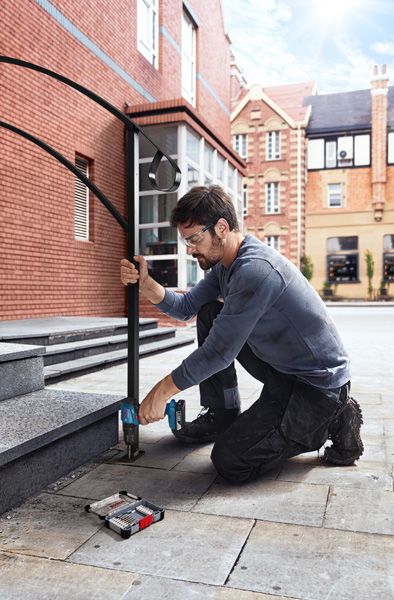 一名佩戴安全设备的人员钻入石阶，安装金属扶手。.