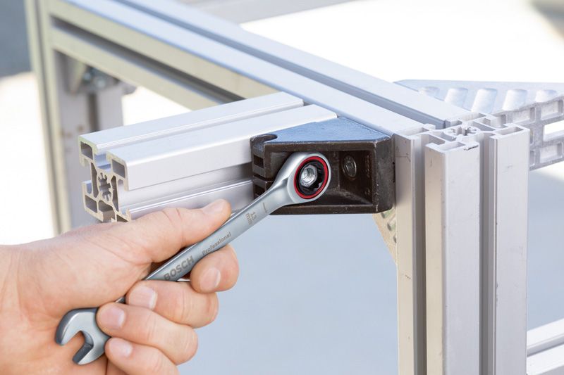 一个人用组合扳手拧紧金属框架上的螺栓。.