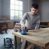 一名佩戴安全设备的人员正在使用连接的轨道砂光机打磨木门。.