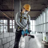 一名佩戴安全设备的人员使用动力切割机切割 AAC 块。.