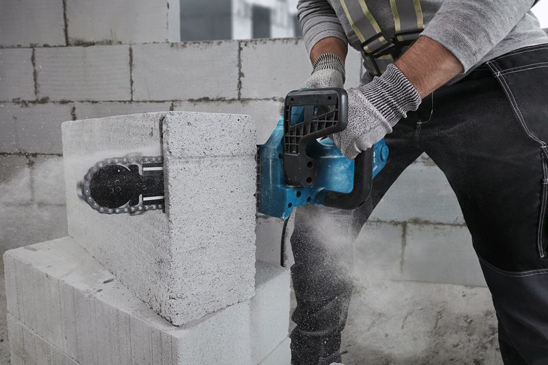 一名佩戴安全设备的人员使用电动切割机切割 AAC 块。.