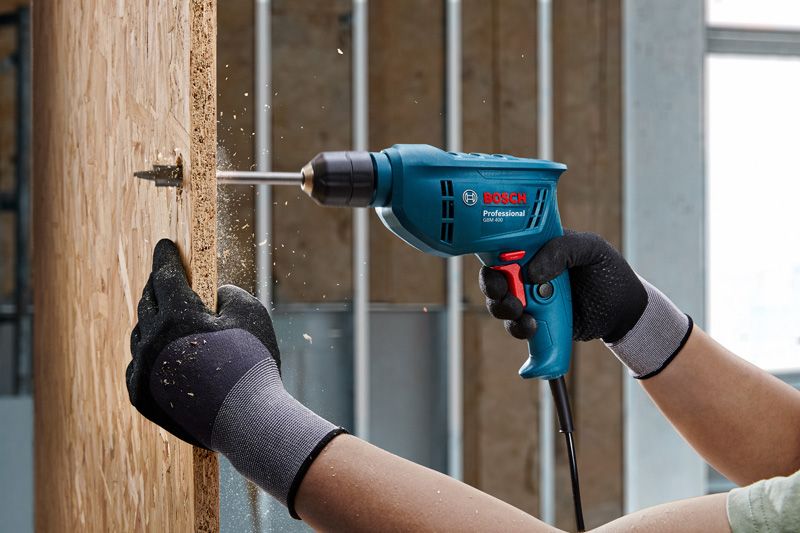 一名佩戴安全设备的人员正在向木板上钻孔。.