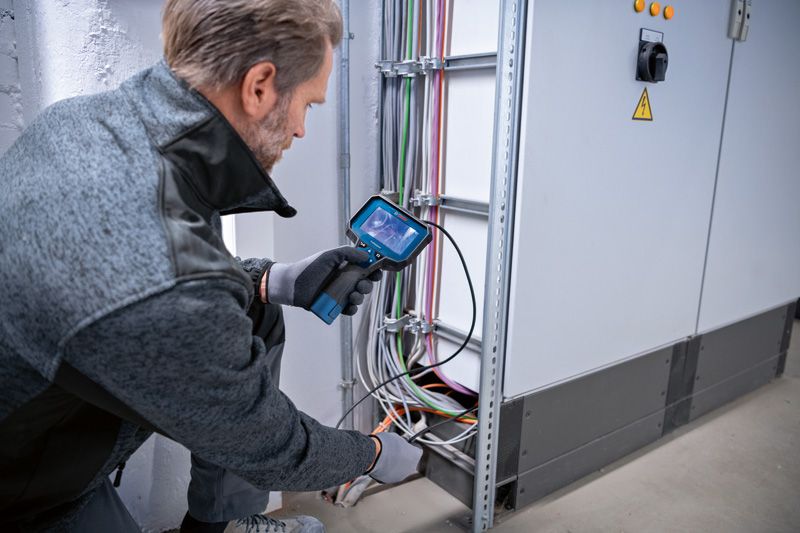 一名佩戴安全装备的人员使用内窥镜检查电缆。