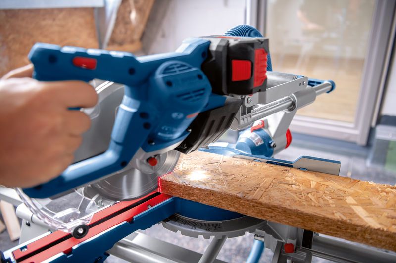 一个人在工作台上用无绳斜切锯切割木板。.