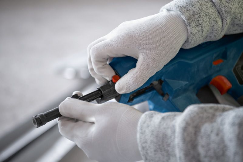 佩戴安全设备的人员正在调整无绳混凝土钉枪。.